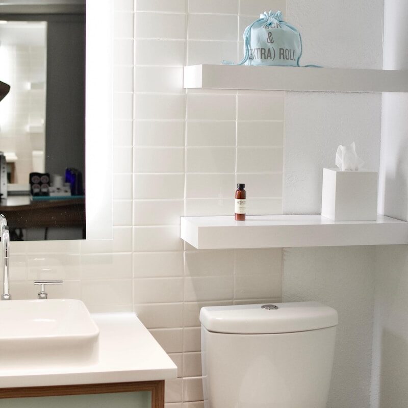 white ceramic toilet seat with white wooden shelf